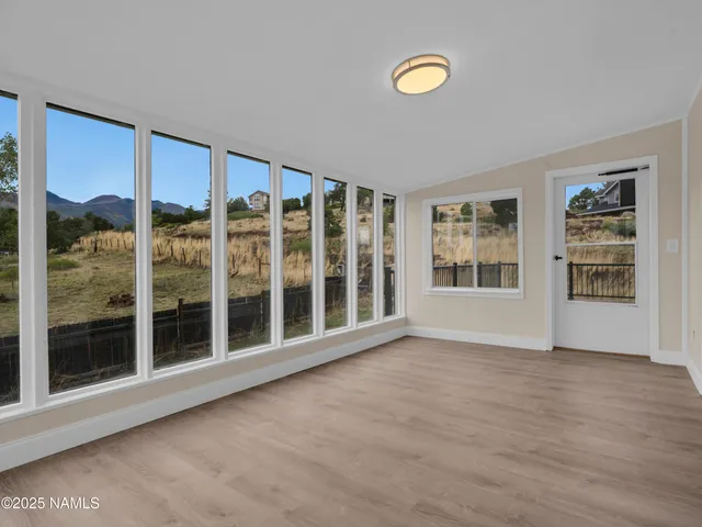 an empty room with a chandelier fan and windows