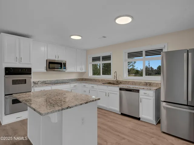 a kitchen with granite countertop a sink cabinets and stainless steel appliances