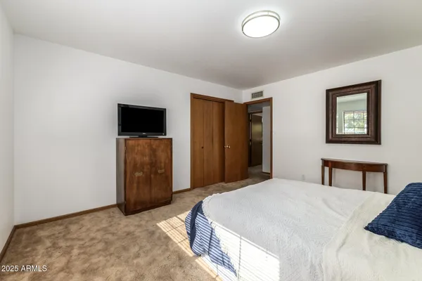 a bedroom with a bed and a refrigerator