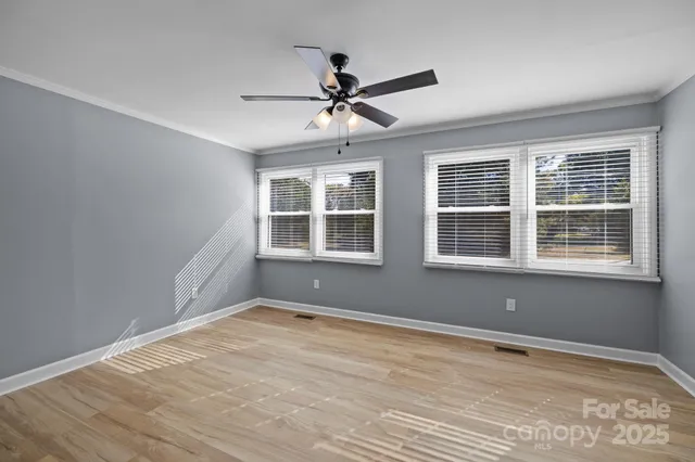 a view of an empty room with window and a ceiling fan
