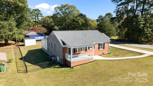 an aerial view of a house with swimming pool and large trees