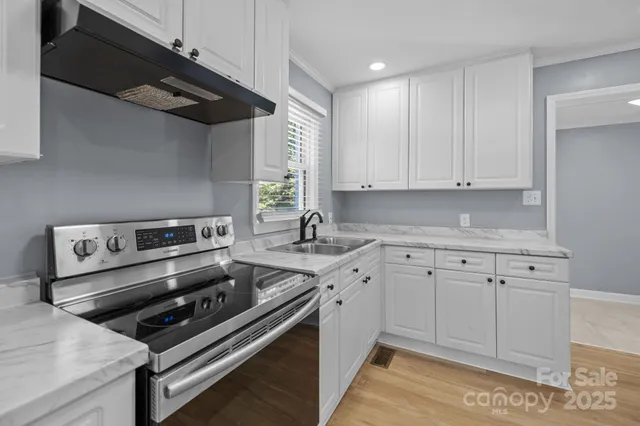 a kitchen with stainless steel appliances a stove a sink and white cabinets
