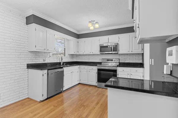 a kitchen with granite countertop a sink cabinets and stainless steel appliances