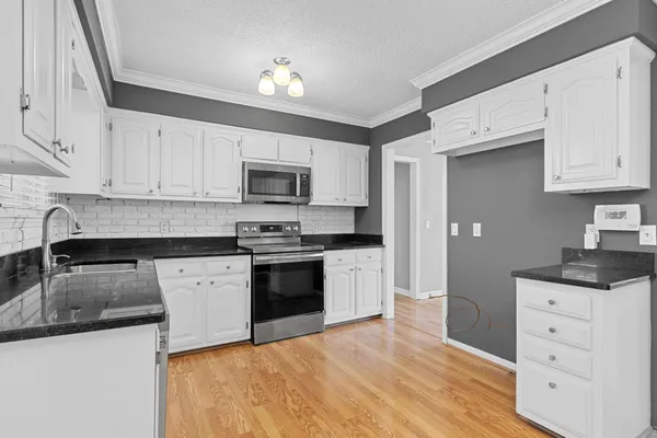 a kitchen with granite countertop white cabinets and white appliances