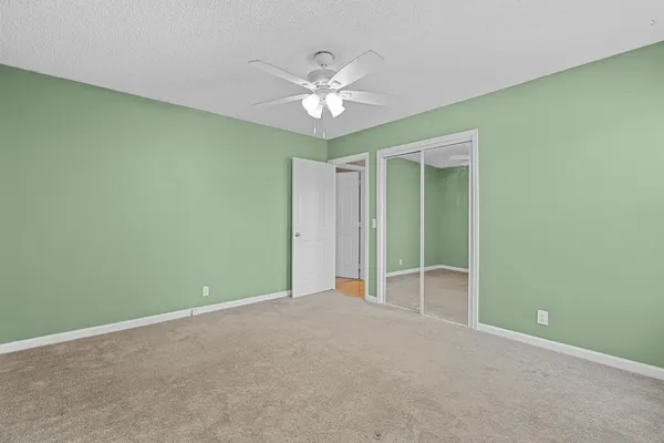 an empty room with windows and ceiling fan