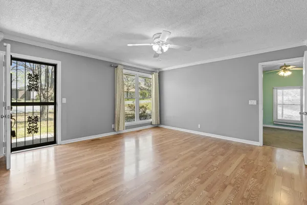 a view of an empty room with wooden floor and a window