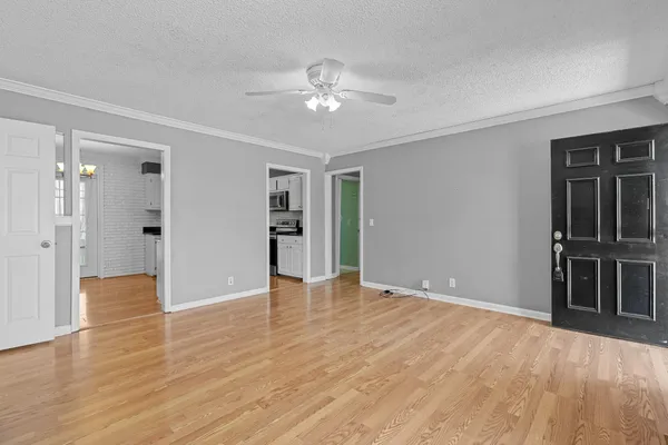 a view of an empty room with kitchen and a window