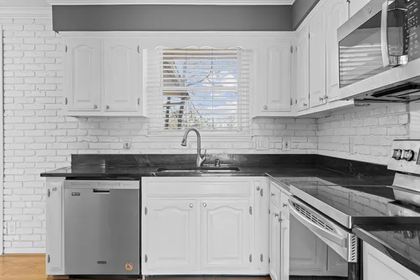 a kitchen with granite countertop stainless steel appliances cabinets a sink and a counter top space