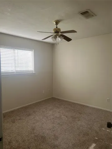 an empty room with a window and a fan