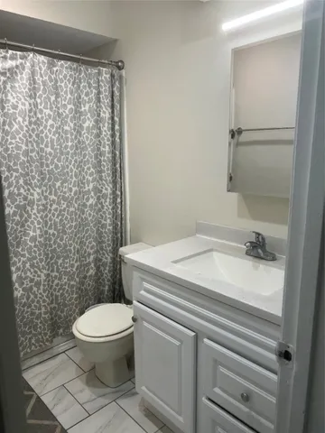 a bathroom with a granite countertop toilet and a shower