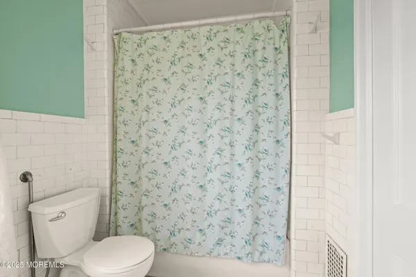 a bathroom with a toilet and a shower curtain