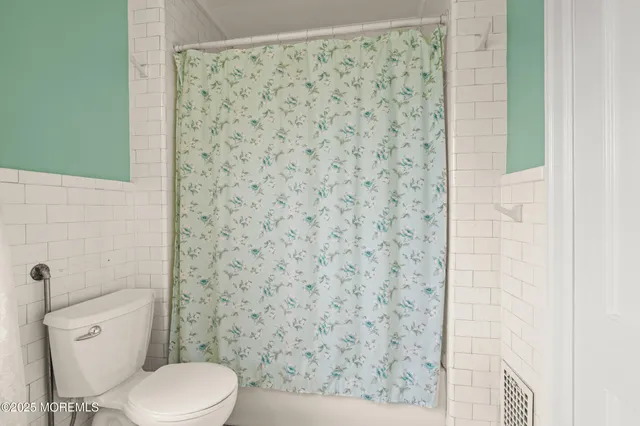 a bathroom with a toilet and a shower curtain