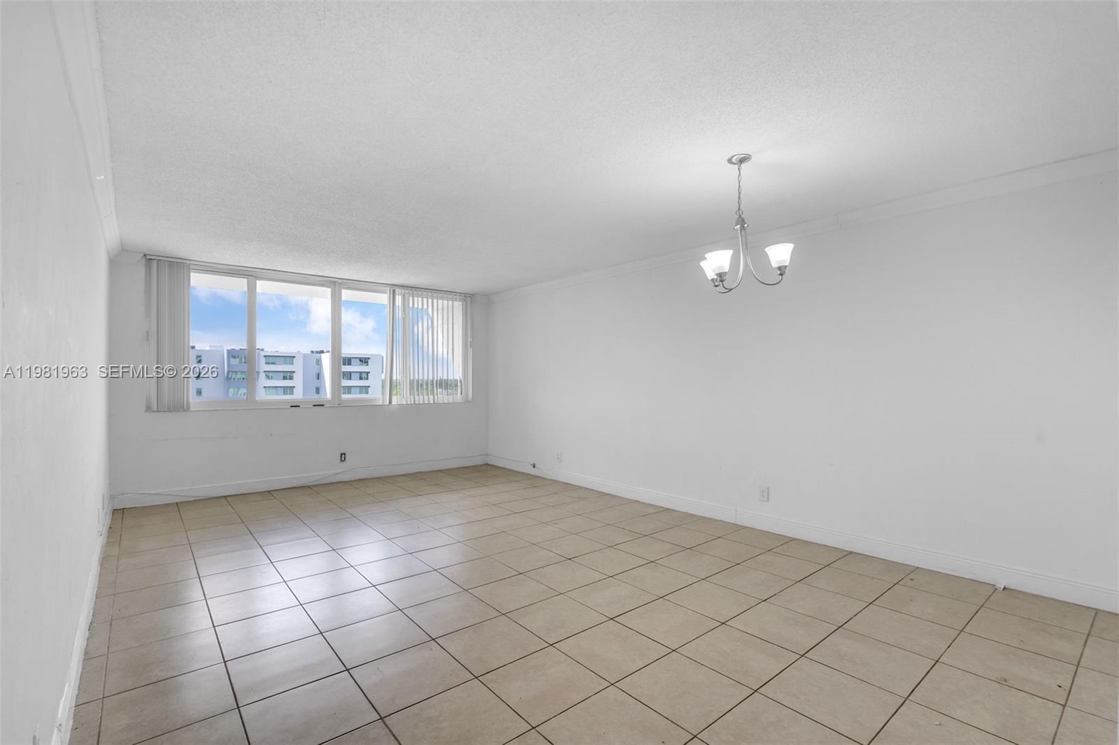 9143 Southwest 77th Avenue, Unit B710 Miami, FL 33156 - Photo 5 of 28 an empty room with chandelier fan and window
