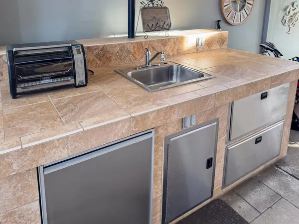 a open kitchen with cabinets a stove a sink and a dining table with wooden floors