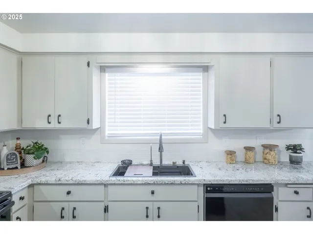 a kitchen with granite countertop white cabinets and a window