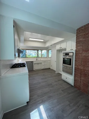 a kitchen with cabinets wooden floor and stainless steel appliances