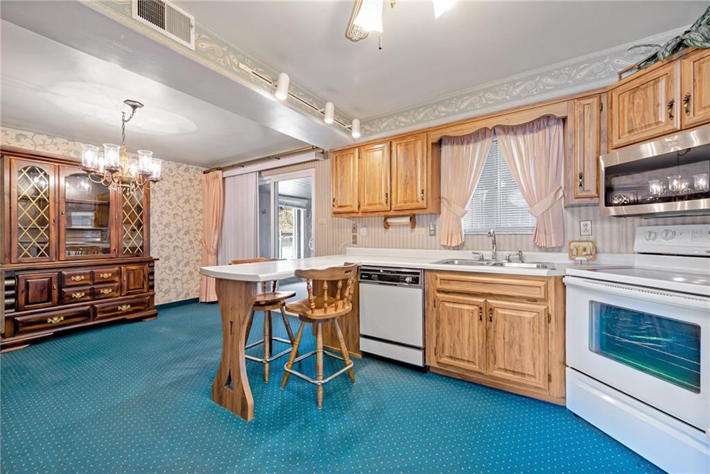 709 Indian Hill Road Rostraver Township, PA 15012 - Photo 15 of 25 a kitchen with stainless steel appliances granite countertop a stove a sink dishwasher and a microwave with wooden floor