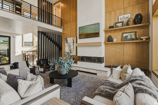 923 North Emery Lane Elk Ridge, UT 84651 - Photo 10 of 101 Two-story living area featuring a linear fireplace with a stone hearth, wood-paneled accent walls, and a multi-level open-tread staircase with metal railings