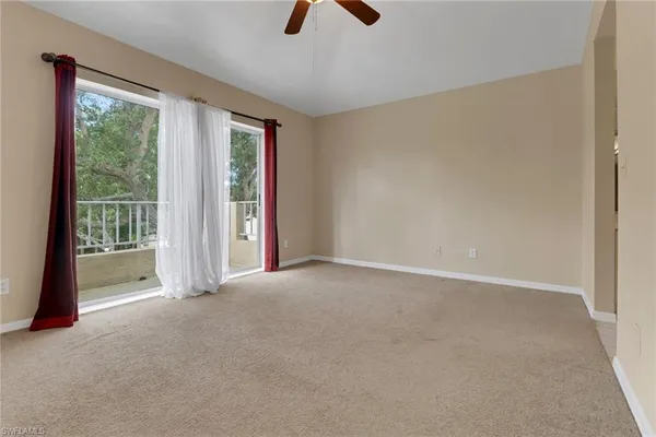 an empty room with chandelier fan and windows