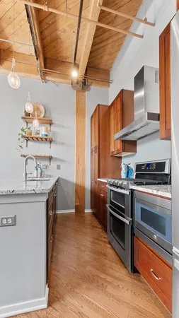 a kitchen with stainless steel appliances granite countertop a sink a stove and a wooden floors
