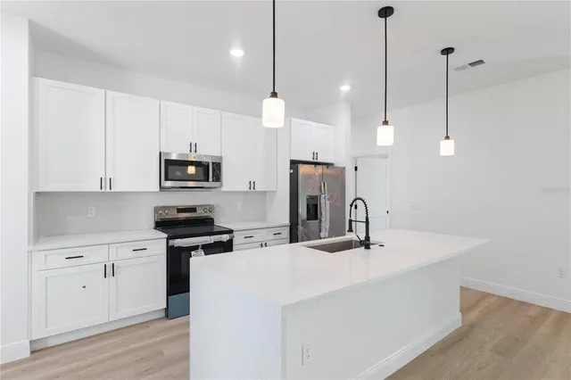 a kitchen with white cabinets and stainless steel appliances