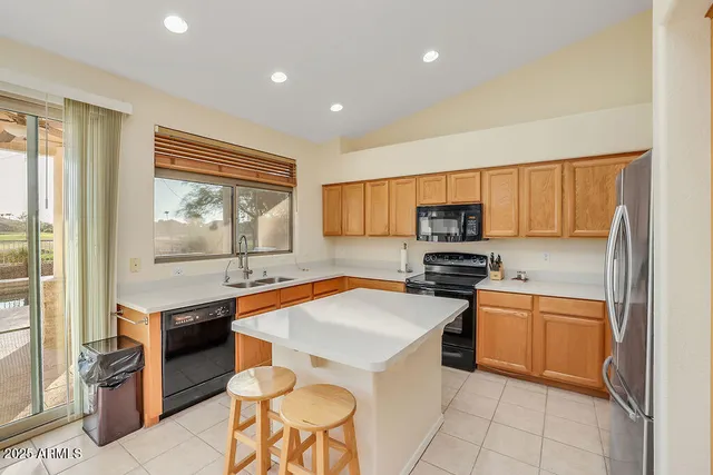 a kitchen with stainless steel appliances granite countertop a stove top oven a sink dishwasher and a refrigerator with wooden floor