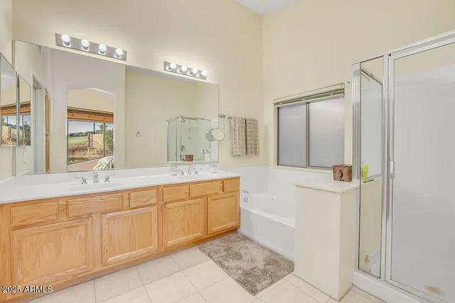 a spacious bathroom with a double vanity sink a mirror a shower and a bathtub