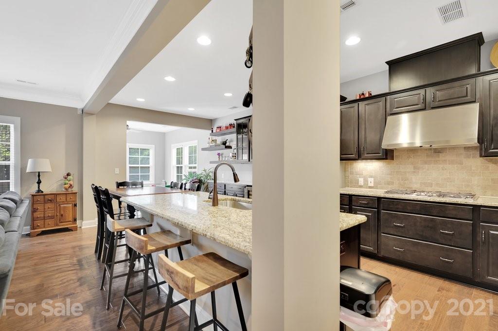 693 Old Cove Road Tega Cay, SC 29708 - Photo 6 of 38 a kitchen with stainless steel appliances granite countertop table chairs and wooden floor