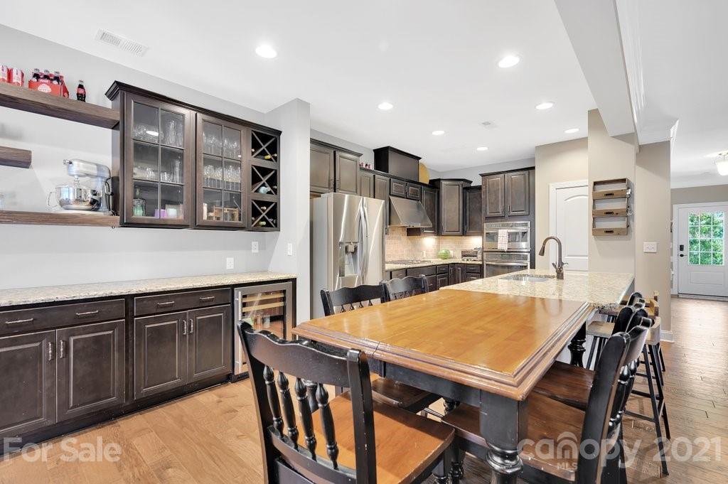 693 Old Cove Road Tega Cay, SC 29708 - Photo 7 of 38 a kitchen with stainless steel appliances granite countertop a dining table chairs and refrigerator