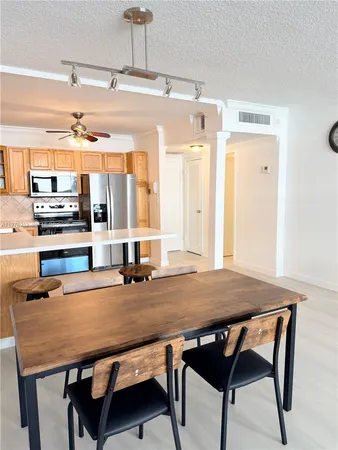 a room with stainless steel appliances a table chairs and wooden floor