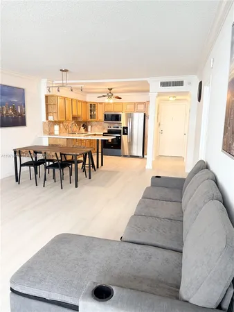 a living room with couches and kitchen view with wooden floor
