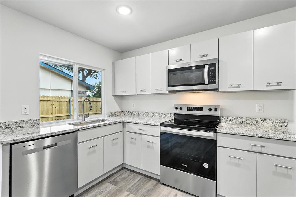 4613 Tarry Drive Garland, TX 75043 - Photo 11 of 38 a kitchen with granite countertop white cabinets sink and stainless steel appliances