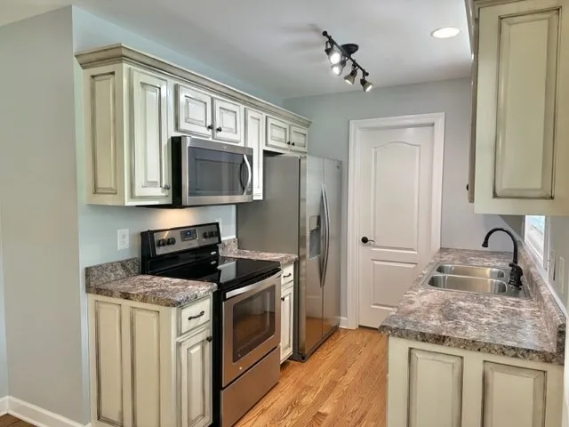 a kitchen with stainless steel appliances granite countertop a sink stove and refrigerator