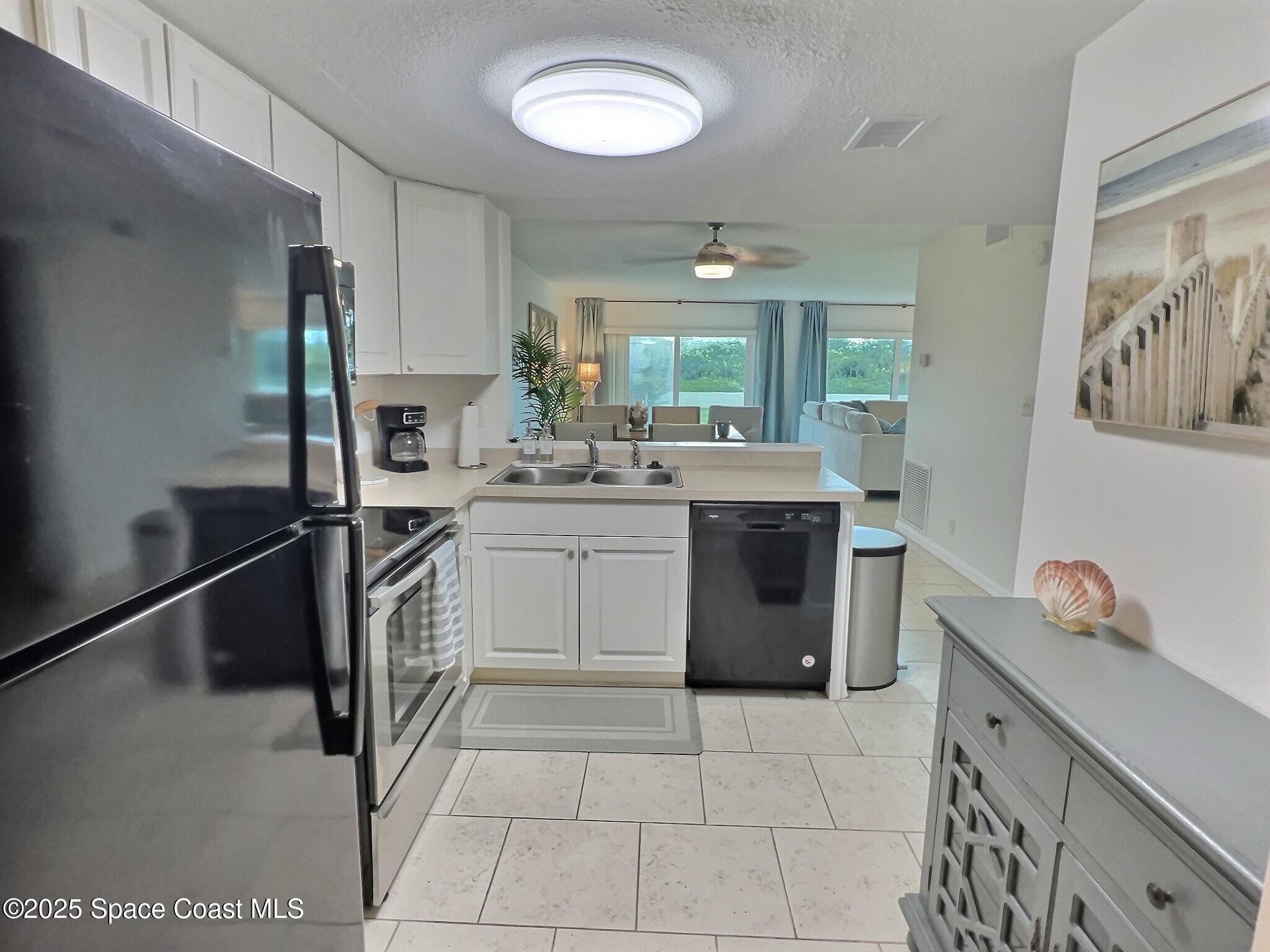 4570 Ocean Beach Boulevard, Unit 104 Cocoa Beach, FL 32931 - Photo 11 of 18 a kitchen with a stove sink and cabinets