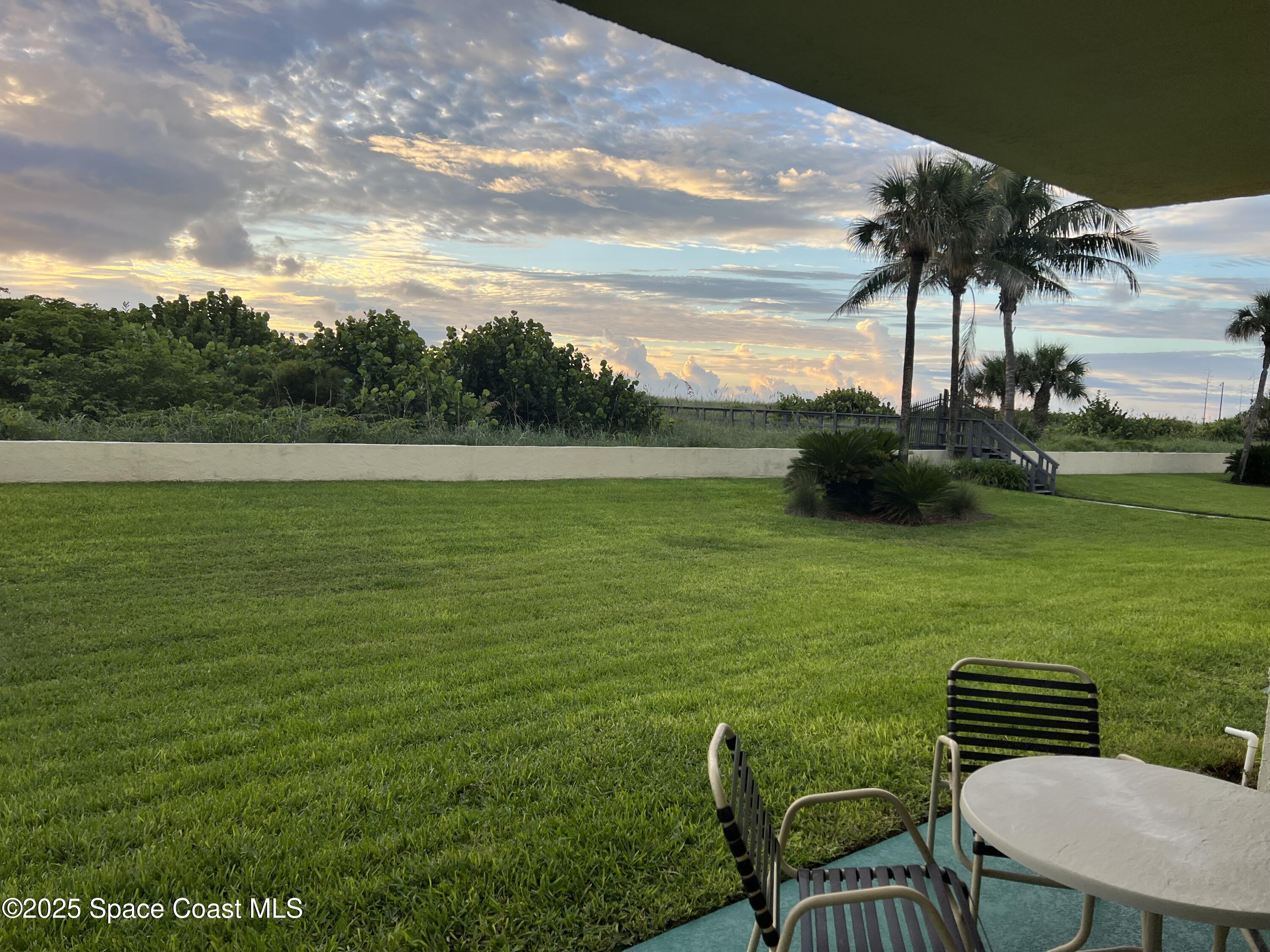 4570 Ocean Beach Boulevard, Unit 104 Cocoa Beach, FL 32931 - Photo 16 of 18 a view of a table and chairs in the garden