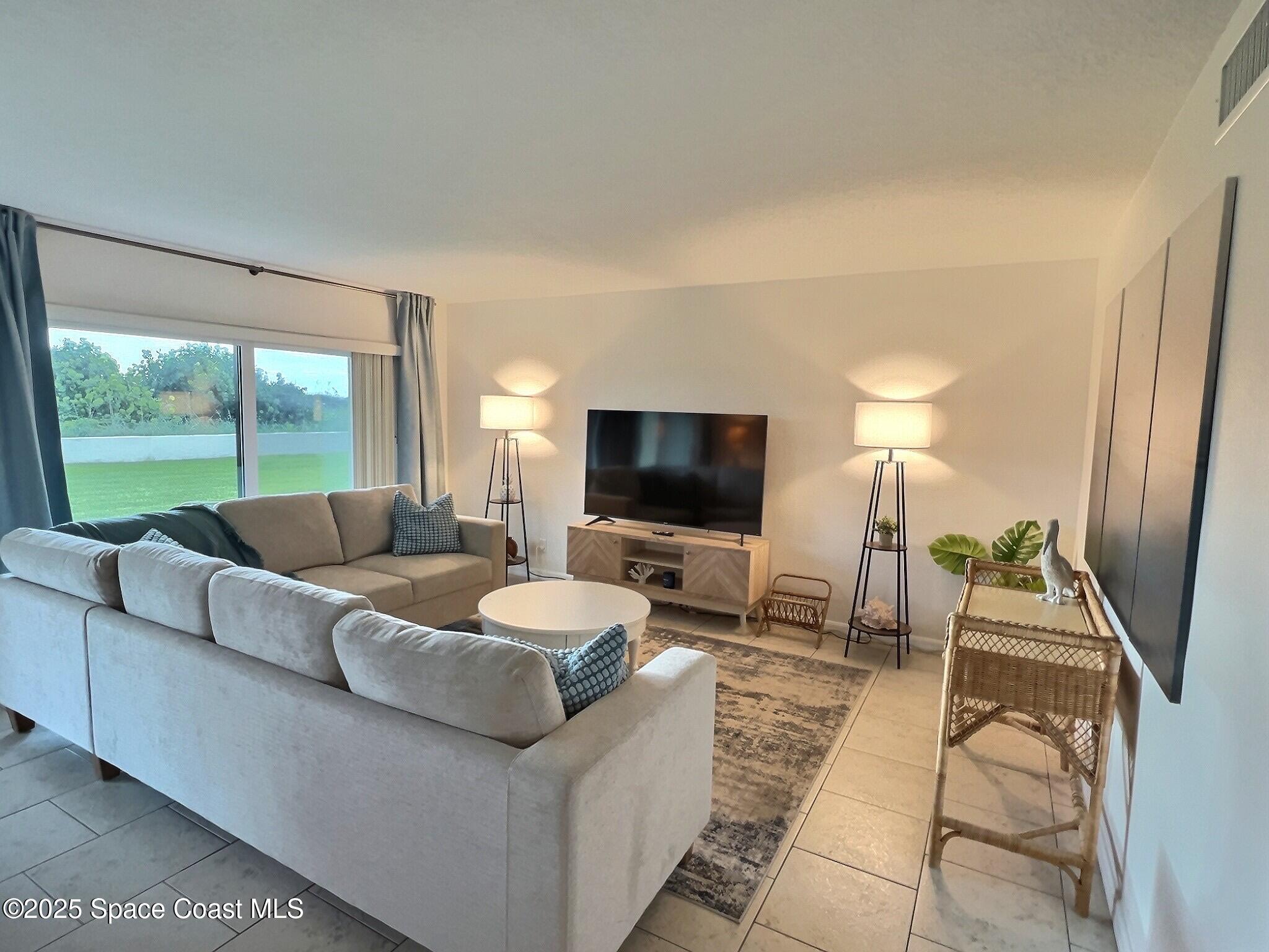 4570 Ocean Beach Boulevard, Unit 104 Cocoa Beach, FL 32931 - Photo 4 of 18 a living room with furniture and a flat screen tv