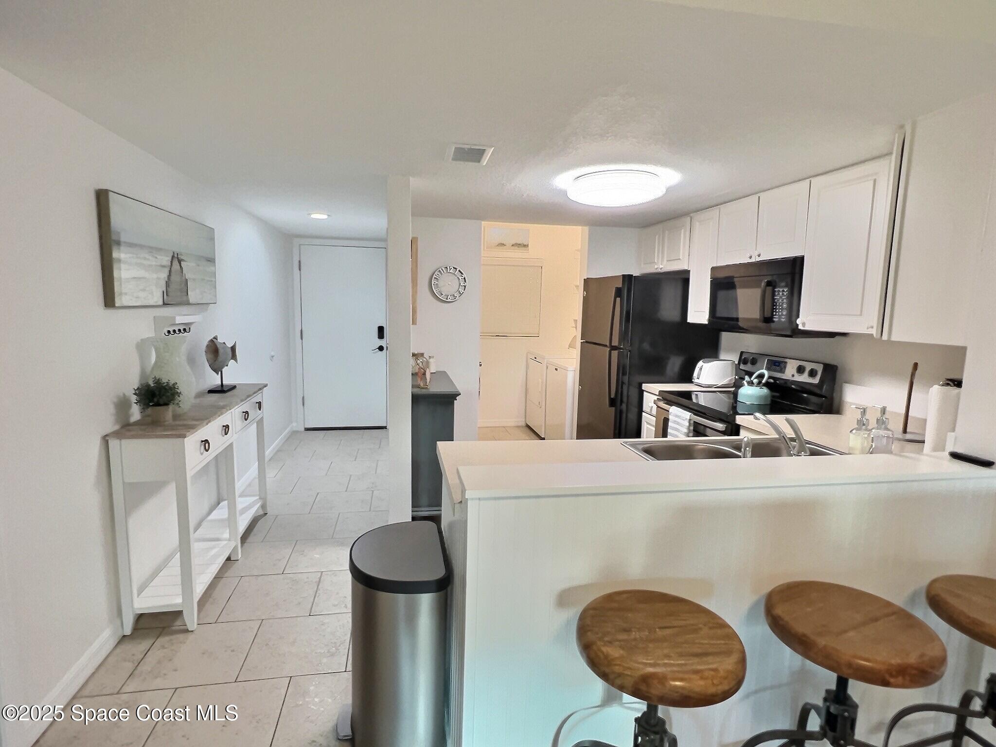 4570 Ocean Beach Boulevard, Unit 104 Cocoa Beach, FL 32931 - Photo 9 of 18 a kitchen with stainless steel appliances granite countertop a sink refrigerator and cabinets