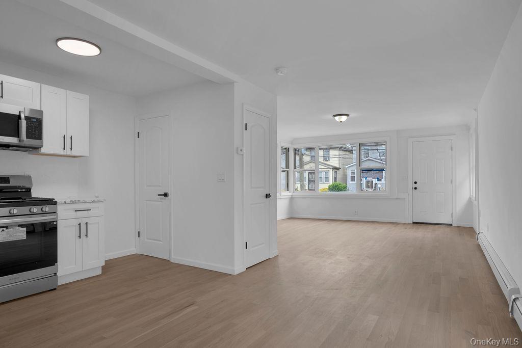 173-62 103rd Road Queens, NY 11433 - Photo 5 of 23 a view of an empty room with window and wooden floor