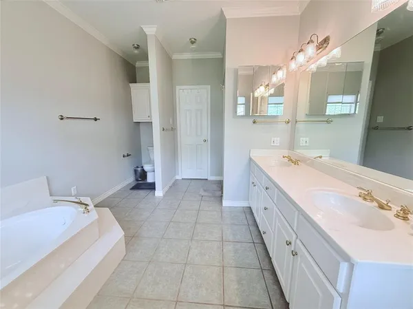 a spacious bathroom with a double vanity sink mirror and bathtub