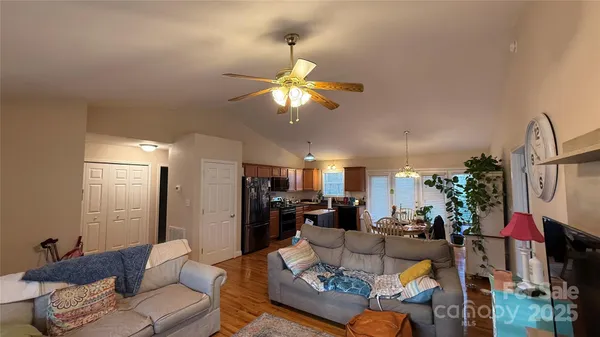 a living room with furniture kitchen view and a chandelier