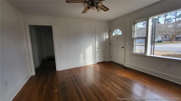 a view of an empty room with a window and wooden floor