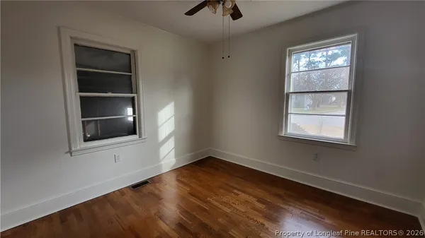 an empty room with wooden floor and windows