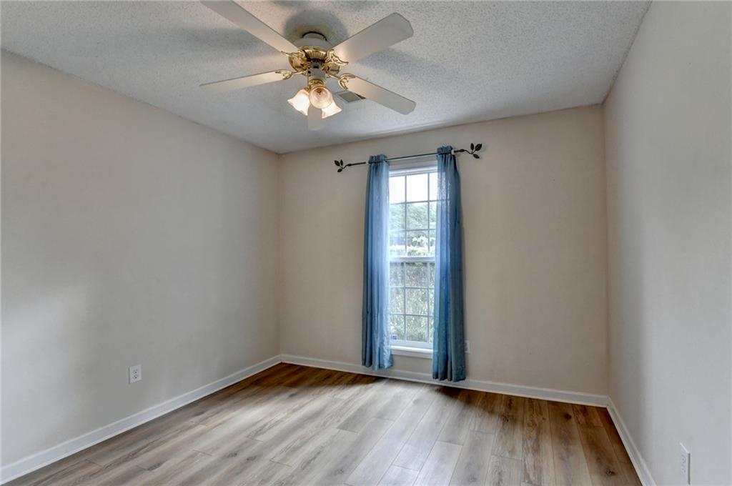 601 Bowling Lane Winder, GA 30680 - Photo 35 of 45 an empty room with wooden floor chandelier fan and windows