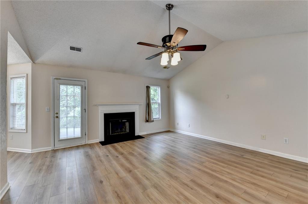 601 Bowling Lane Winder, GA 30680 - Photo 10 of 45 an empty room with windows fireplace and wooden floor