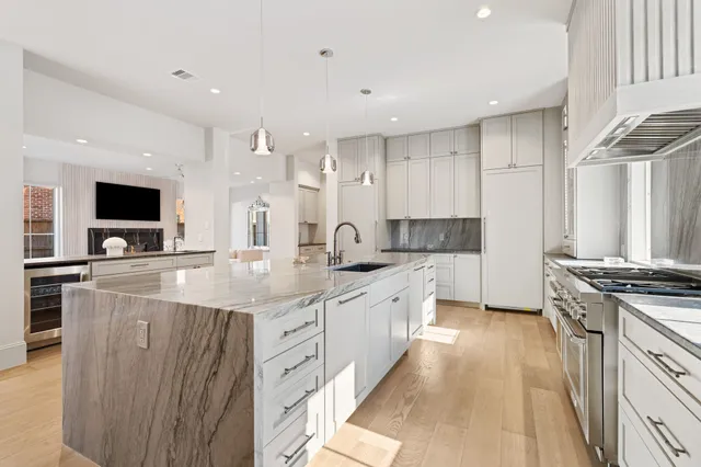 a large kitchen with stainless steel appliances a stove a sink and a microwave