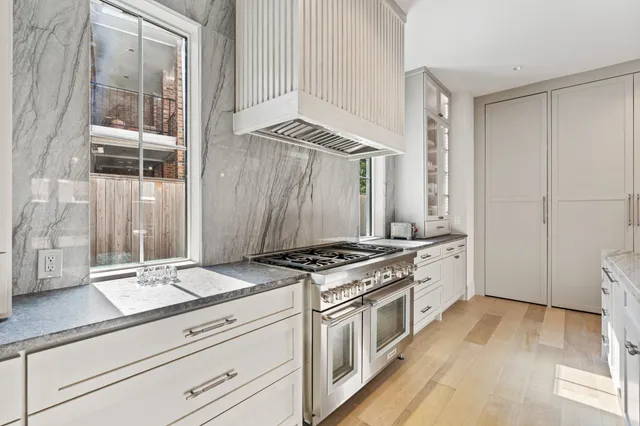 a kitchen with stainless steel appliances granite countertop a stove and a white cabinets