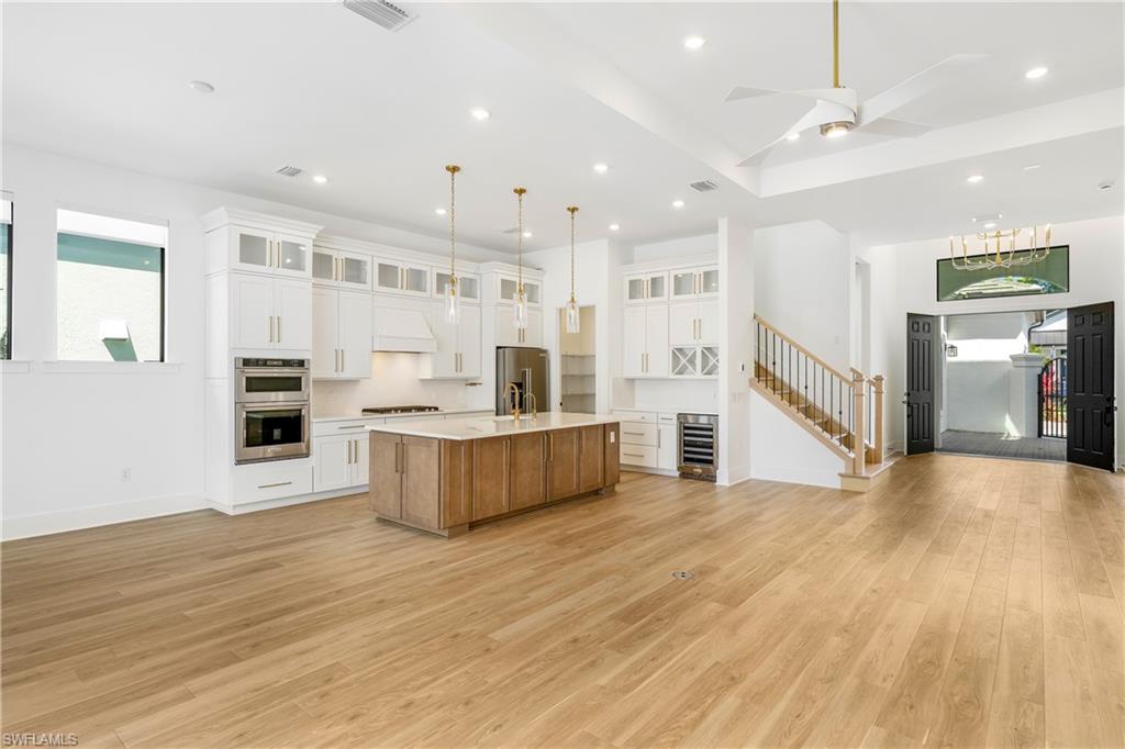 9560 Caymas Terrace Naples, FL 34114 - Photo 2 of 40 a large kitchen with stainless steel appliances kitchen island a large counter top and a wooden floor