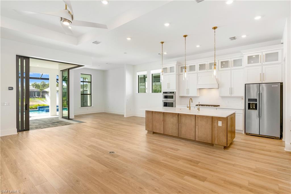 9560 Caymas Terrace Naples, FL 34114 - Photo 3 of 40 a large kitchen with stainless steel appliances kitchen island granite countertop a large cabinets a sink and wooden floor