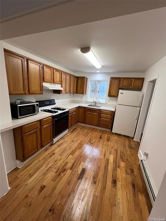 493 Munsell Road East Patchogue, NY 11772 - Photo 14 of 14 a kitchen with wooden floors and stainless steel appliances