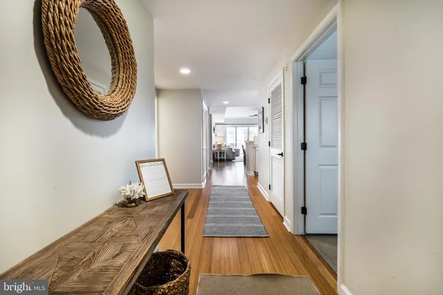 a view of a hallway with wooden floor and a bathroom